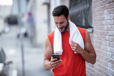 Genç sporcu dışarıda koşuyor. Açık hava eğitiminden sonra yakışıklı bir adam dinleniyor..