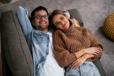 Genç ve sevgi dolu bir çift kanepede dinleniyor. Mutlu çift evde eğleniyor..