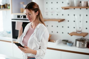 Mutfaktaki kadın. Mutfakta telefon kullanan güzel bir kadın..