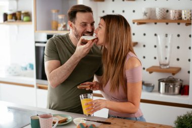 Genç çift evde sandviç yapıyor. Sevgi dolu çift mutfakta eğleniyor..
