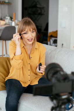 Kadın video kaydedicisi, kanalı için makyaj dersi kaydediyor. Sosyal medyada paylaşmak için makyaj dersi alan genç ve güzel bir kadın..