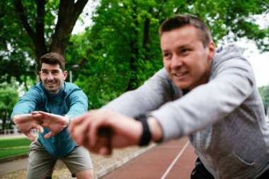 Yarış pistinde egzersiz yapan genç adamlar. Dışarıda antrenman yapan iki genç arkadaş..