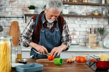 Yaşlı adam yemek yapıyor. Mutfakta kıdemli adam var..