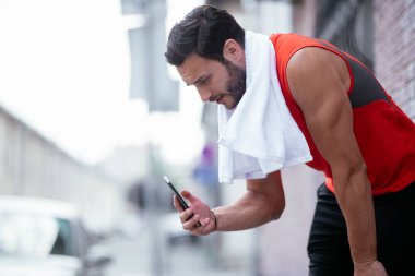 Genç sporcu dışarıda koşuyor. Açık hava eğitiminden sonra yakışıklı bir adam dinleniyor..