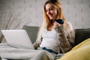 Güzel sarışın kadın dizüstü bilgisayarında film izliyor..