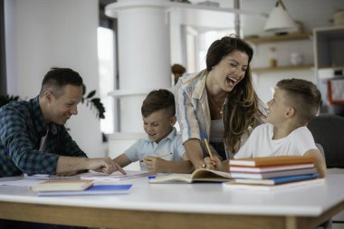 Anne ve baba oğullarına ev ödevlerinde yardım ederler.