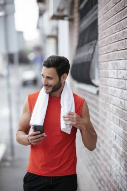 Genç sporcu dışarıda koşuyor. Açık hava eğitiminden sonra yakışıklı bir adam dinleniyor..