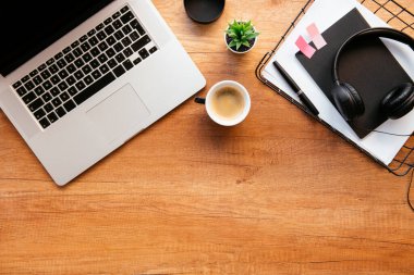 Ofis masasının en üst görüntüsü. Dizüstü bilgisayarlı ahşap masa, bir fincan kahve ve malzeme..