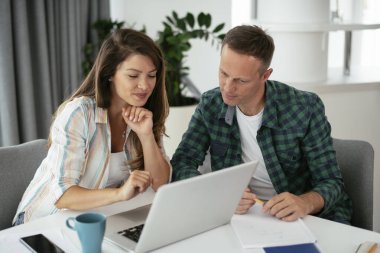 Erkek ve kadın evde dizüstü bilgisayar kullanarak çalışıyor.