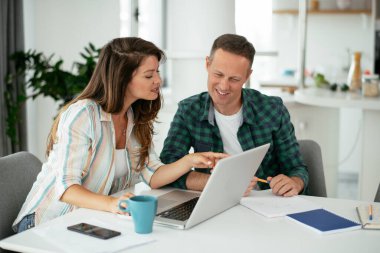 Erkek ve kadın evde dizüstü bilgisayar kullanarak çalışıyor.