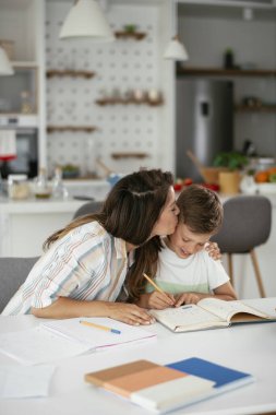 Güzel, genç bir anne çocuğuna ödevlerinde yardım ediyor..