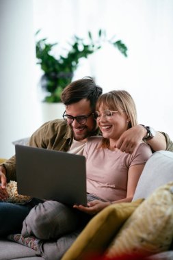 Dizüstü bilgisayarda film izleyen genç bir çift. Sevgili çift evde eğleniyor..