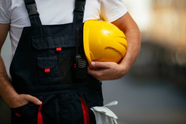 Sarı miğferi elinde tutan fabrika işçisi