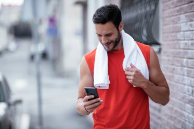 Genç sporcu dışarıda koşuyor. Açık hava eğitiminden sonra yakışıklı bir adam dinleniyor..