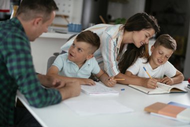 Anne ve baba oğullarına ev ödevlerinde yardım ederler.