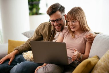 Dizüstü bilgisayarda film izleyen genç bir çift. Sevgili çift evde eğleniyor..