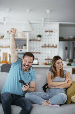 Karı koca oturma odasında joysticklerle oyun oynuyorlar. Sevgili çift evde video oyunu oynuyor..