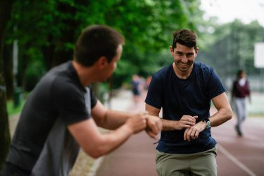 Gençler yarış pistinde antrenman yapıyor. İki genç arkadaş atletizm pistinde koşuyor.