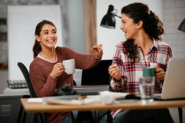Açık uzay ofisinde konuşan ve gülen mutlu iş kadınları