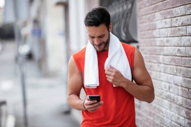 Genç sporcu dışarıda koşuyor. Açık hava eğitiminden sonra yakışıklı bir adam dinleniyor..