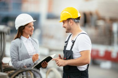 Müdür ve fabrika işçisi üretim hattında konuşuyor.
