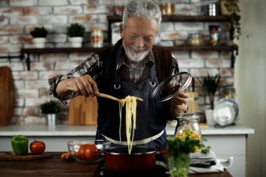 Yaşlı adam yemek yapıyor. Mutfakta kıdemli adam var..