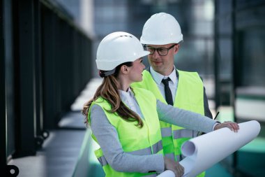 İnşaat alanının yanında durup projeyi tartışan gülümseyen mimarların portresi