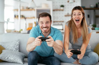 Karı koca oturma odasında joysticklerle oyun oynuyorlar. Sevgili çift evde video oyunu oynuyor..