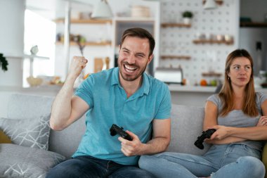 Karı koca oturma odasında joysticklerle oyun oynuyorlar. Sevgili çift evde video oyunu oynuyor..