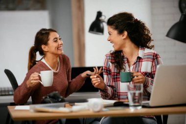 Açık uzay ofisinde konuşan ve gülen mutlu iş kadınları