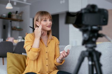 Kadın video kaydedicisi, kanalı için makyaj dersi kaydediyor. Sosyal medyada paylaşmak için makyaj dersi alan genç ve güzel bir kadın..