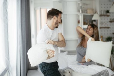 Çift evde eğleniyor, yastıklarla kavga ediyor.