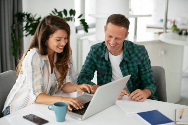 Erkek ve kadın evde dizüstü bilgisayar kullanarak çalışıyor.