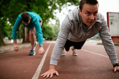 Yarış pistinde egzersiz yapan genç adamlar. Dışarıda antrenman yapan iki genç arkadaş..
