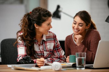 Açık uzay ofisinde konuşan ve gülen mutlu iş kadınları