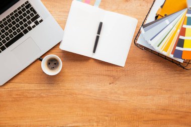 Ofis masasının en üst görüntüsü. Dizüstü bilgisayarlı ahşap masa, bir fincan kahve ve malzeme..