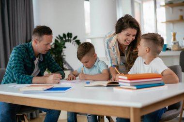 Anne ve baba oğullarına ev ödevlerinde yardım ederler.