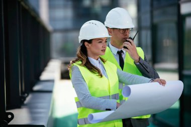 İnşaat alanının yanında durup projeyi tartışan gülümseyen mimarların portresi