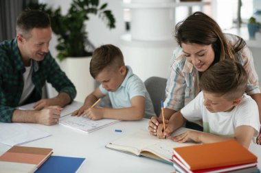 Anne ve baba oğullarına ev ödevlerinde yardım ederler.