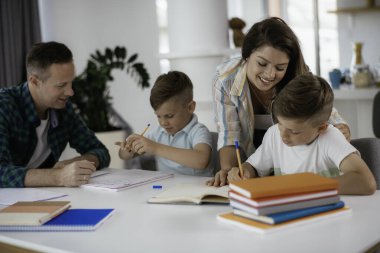 Anne ve baba oğullarına ev ödevlerinde yardım ederler.