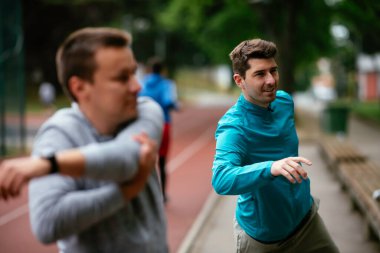 Yarış pistinde egzersiz yapan genç adamlar. Dışarıda antrenman yapan iki genç arkadaş..
