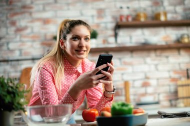 Mutfaktaki kadın. Mutfakta telefon kullanan güzel bir kadın..