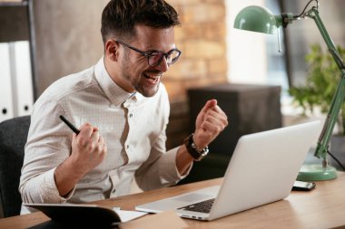 Ofiste dizüstü bilgisayarıyla çalışan bir iş adamı. Ofiste bir proje üzerinde çalışan şık bir işadamı..