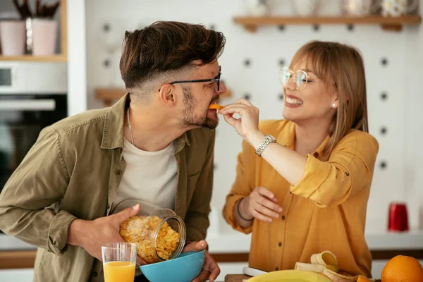 Genç çift evde kahvaltı hazırlıyor. Sevgi dolu çift mutfakta mısır gevreği yiyor..
