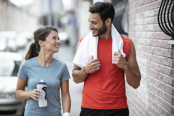 Athletic couple is having a rest after jogging in the city. Happy couple enjoying in the morning..