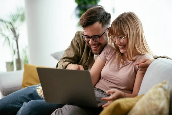 Young couple watching movie on laptop. Loving couple enjoying at home.