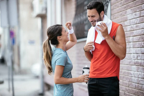 Athletic couple is having a rest after jogging in the city. Happy couple enjoying in the morning..