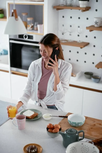 Woman in kitchen. Beautiful woman using phone in kitchen.