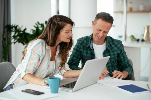 Erkek ve kadın evde dizüstü bilgisayar kullanarak çalışıyor.