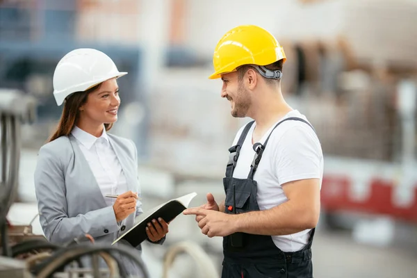 Manager and factory worker talk at production line